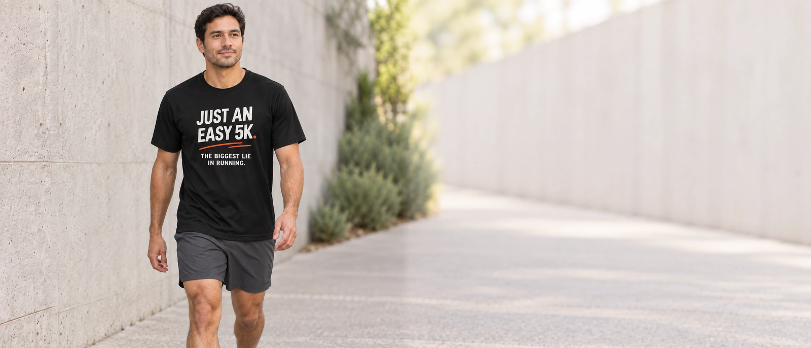 Model walking outdoors in the Vintage Black Just an Easy 5K tee with white lettering and orange accents.